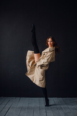 young beautiful girl in the studio on a black background, she is wearing a trench coat and black lingerie