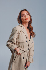 young beautiful girl in the studio, on a black background, she is wearing a trench coat and black lingerie