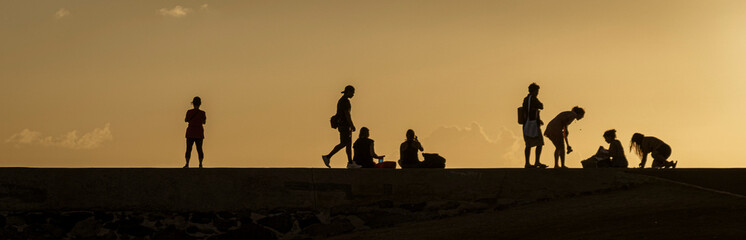 Fototapeta na wymiar Silhouettes of people watching the sunset on Oahu, Hawaii.