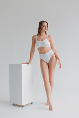 girl gymnast, in a white uniform, panties and top, in the studio on a white background shows exercises