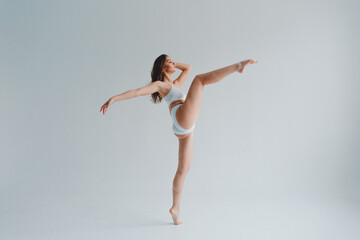 Fototapeta na wymiar girl gymnast, in a white uniform, panties and top, in the studio on a white background shows exercises