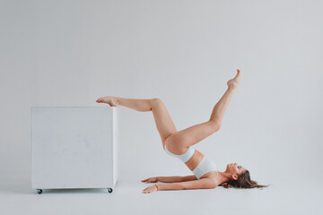 girl gymnast, in a white uniform, panties and top, in the studio on a white background shows exercises