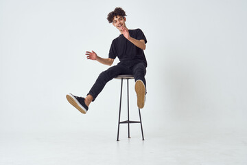 curly guy sitting on a chair posing fashion light background