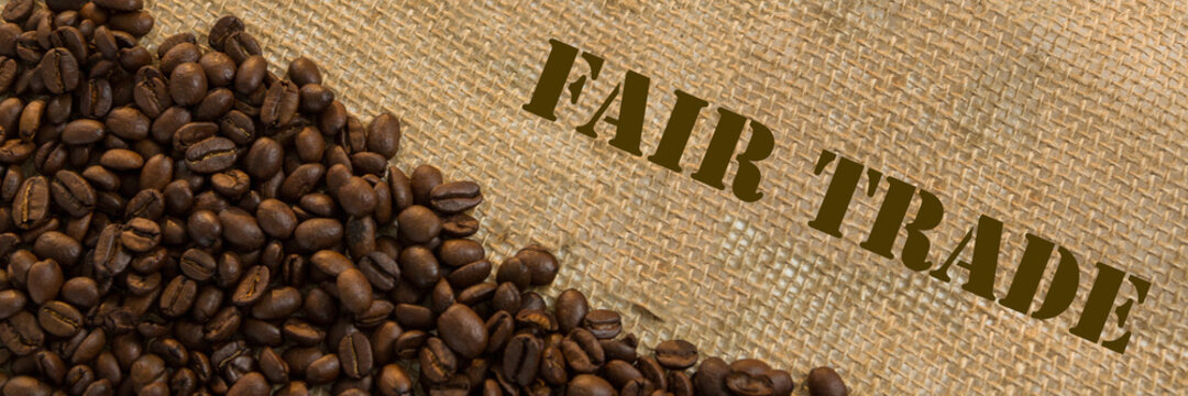 Dark roasted fair trade coffee beans with text Fair Trade. Panoramic image