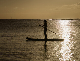 Fototapeta na wymiar Paddle boarder at sunset on Oahu, Hawaii.