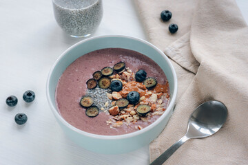 Healthy smoothy bowl with chia seeds, blueberries, nuts and peanut butter. Vegan breakfast, top view
