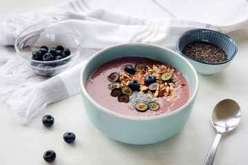 Healthy smoothy bowl with chia seeds, blueberries, nuts and peanut butter. Vegan breakfast