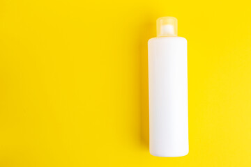 White cosmetic bottle on a yellow background. Space for text.