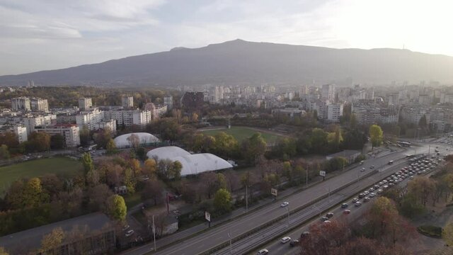 Sofia cityscape main street traffic jam at sunset. Football fields and green parks in business district