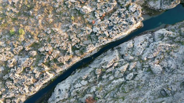 Narrow mountain river flowing through desolate rocky landscape. Stream bed cut deep into stones. Texture of rough barren terrain on the banks of Cijevna (Cem) in Montenegro. Aerial footage.