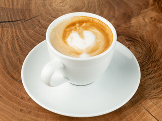 heart shaped cappuccino in white cup on wooden background