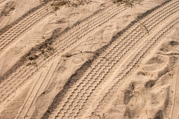 Car tyre tracks on beach sand closeup