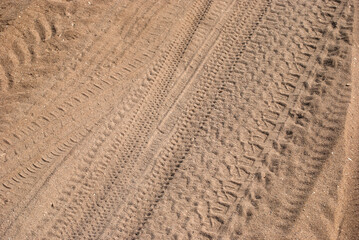 Car tyre tracks on beach sand closeup