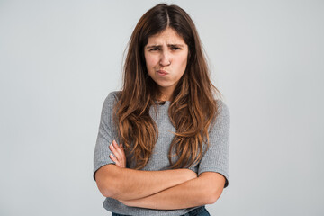 Fototapeta premium Portrait of funny frustrated naughty woman looking at camera with comical resentful unhappy face expression. Indoor studio shot isolated on white background