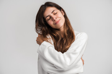 Obraz premium I love myself. Portrait of self-satisfied egoistic woman in urban style embracing herself and smiling with pleasure, feeling self-pride. Studio shot isolated on white background