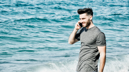 Young man by the sea talking on mobile phone