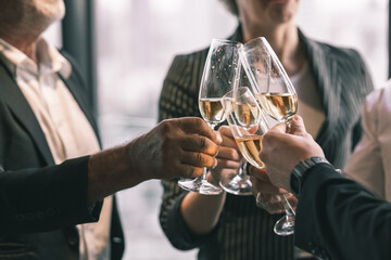 Group of  business partner celebrating their victory. Old business man making a toss to younger business man and woman. They are holding a champagne glass in a hotel lobby with city scape background.