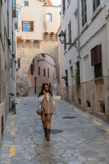 Fototapeta na wymiar mujer hermosa con vestido marrón hablando por teléfono por una calle en el centro de Palma de Mallorca