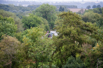 Canal boat, moored on a towpath, viewed through woodland, England, UK.