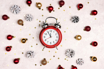 Alarm clock with Christmas balls, cones and stars on on light marble background.