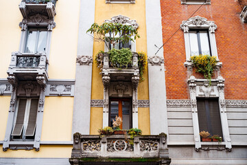 Fototapeta na wymiar Facade of the building with stucco, balconies and flowerpots. Milan, Italy