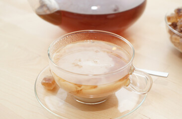 Black tea in a glass with milk in a pot and rock candy sugar 