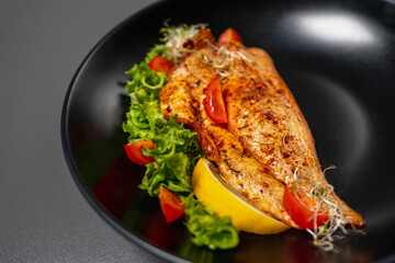 Seafood restaurant dish. Fried fish with tomatoes, lettuce, spices and slice of lemon. White fish...