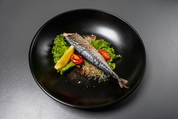Seafood restaurant dish. Baked fish without a head with tomatoes, lettuce, microgreens, spices and a slice of lemon. Protein and vitamin food. Healthy food. Useful dish. Dietary dish.