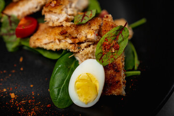 Restaurant dish of chicken fillet. Pieces of brisket fried in batter with cherry tomatoes, leaves and egg. Juicy meat with spices. Chicken white meat cut into pieces.