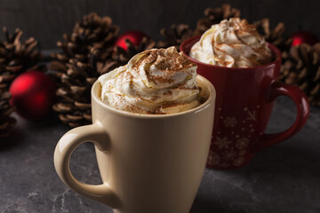Pair of mugs filled with hot chocolate and whipped cream on a dark stone table. Christmas and New...