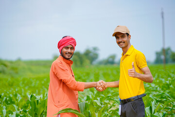 Young indian agronomist or banker shake hand with farmer at agriculture field.