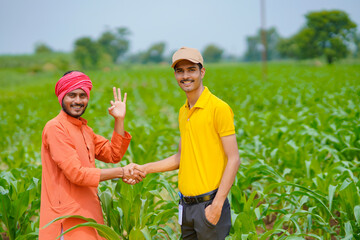 Young indian agronomist or banker shake hand with farmer at agriculture field.