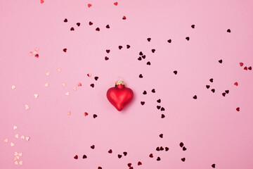 Red confetti in the form of hearts on a pink background and Decoration Valentines day backdrop Flat lay style with minimalistic design Template for banner or party invitation