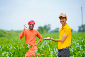 Indian agronomist with farmer at green agriculture field.