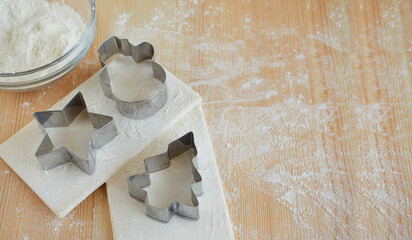 Raw dough, cookie cutters, a cup of flour prepared for baking cookies. Image with copy space