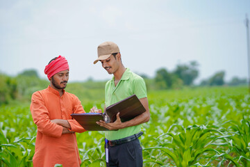 Naklejka na ściany i meble young india bank officer completing paper work with farmers at agriculture field.