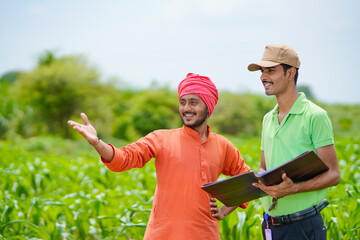 young india bank officer completing paper work with farmers at agriculture field.