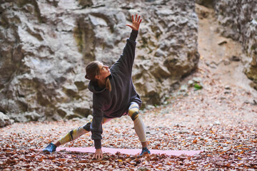 Young woman is engaged in fitness in the autumn park among the rocks. The girl goes in for sports in nature. Healthy Lifestyle.