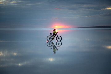 Boy pedaling bike in salt lake at sunset