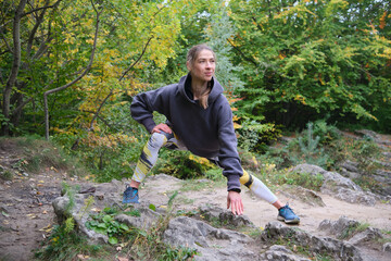 Young woman is engaged in fitness in the autumn park among the rocks. The girl goes in for sports in nature. Healthy Lifestyle.