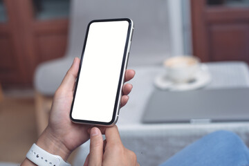 Cell phone mockup image blank white screen.  Woman hand holding, using mobile phone at home.