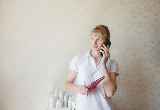 a cosmetologist girl consults a client by phone. pre-registration