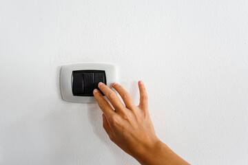 Female hand turning an electricity light switch on the wall