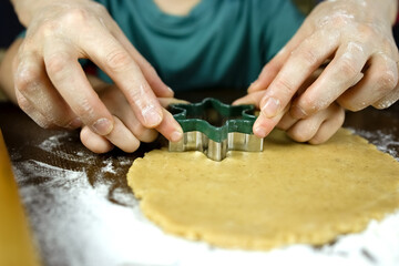 Little kid with mom prepares Christmas cookies using snowflake molds. Cooking food, cookies. DIY Christmas cookies for the holiday. Teaching children.