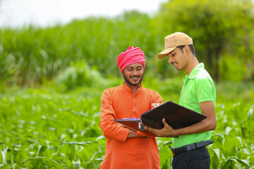 young india bank officer completing paper work with farmers at agriculture field.