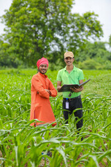 young india bank officer completing paper work with farmers at agriculture field.