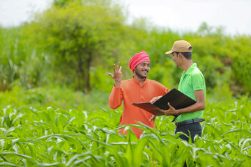 young india bank officer completing paper work with farmers at agriculture field.