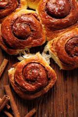 Traditional cinnamon sweet buns on a rustic wooden background, close up view