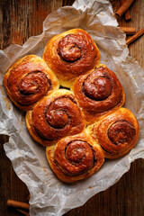 Cinnamon sweet buns on a rustic wooden background, close up view