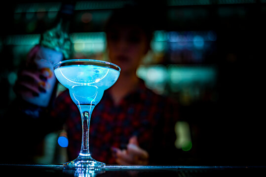 woman bartender hand at the bar or pub to prepare a cocktail Blue Lagoon
